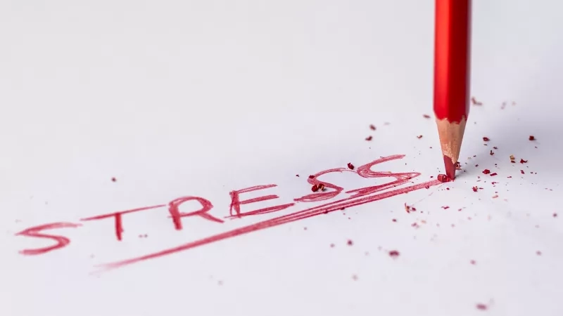 A pencil erases the word stress on a piece of paper.