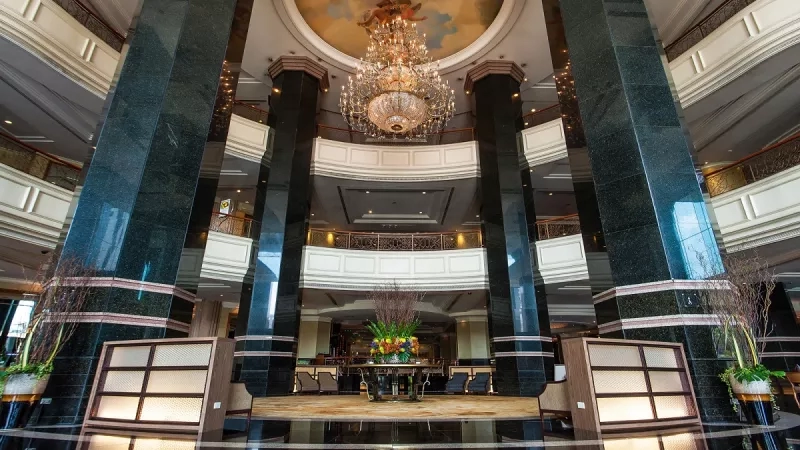 Swissotel lobby with a large chandelier, greenery, and modern architecture.