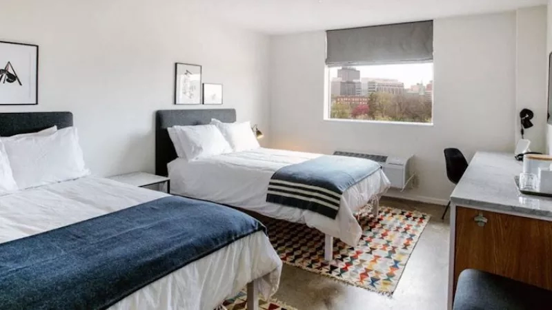 The interior of a room with two beds, a desk, and a window at Trumbull and Porter.