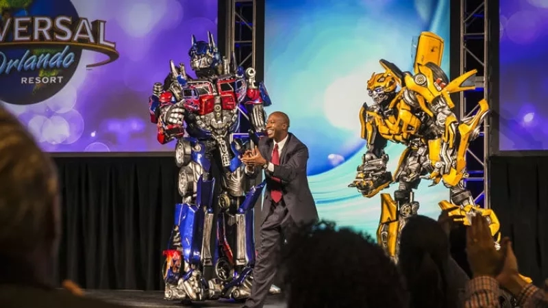 An Orlando resort where a person stands between two Transformers and performs in front of the crowd.
