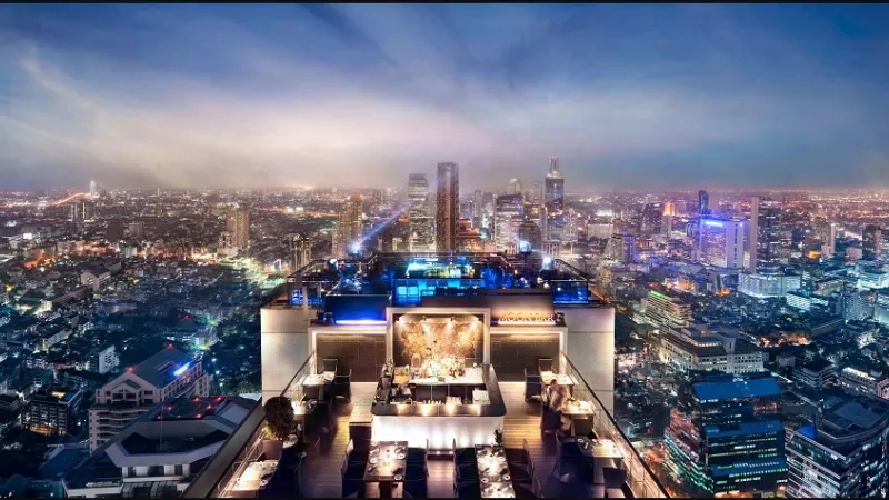 View of Moon Bar at Banyan Tree Bangkok at night with the city skyline in the background.
