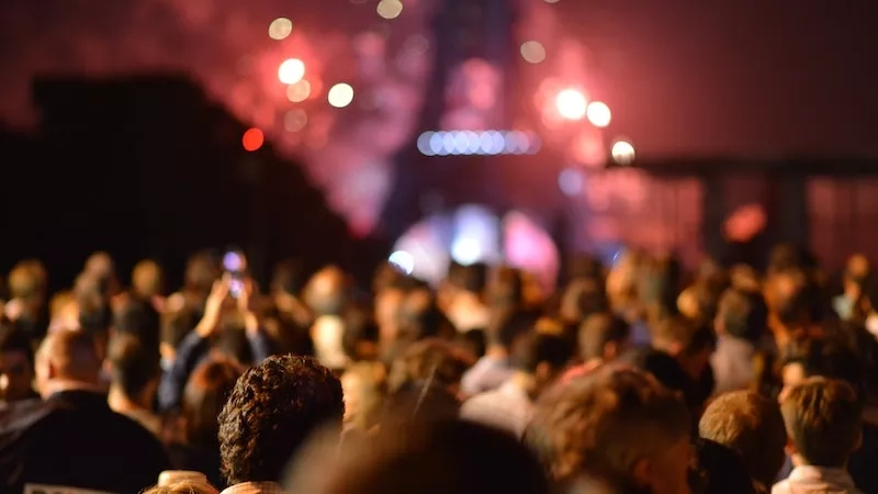 Crowd of people in front of the Eiffel Tower in Paris with the word police on a man's back.