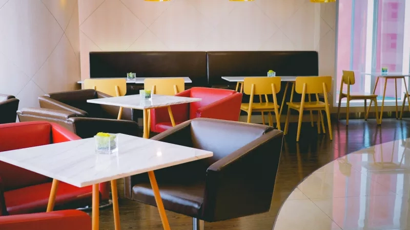 An empty restaurant in the W Hotel with tables, chairs, and glass cups with snacks on them.