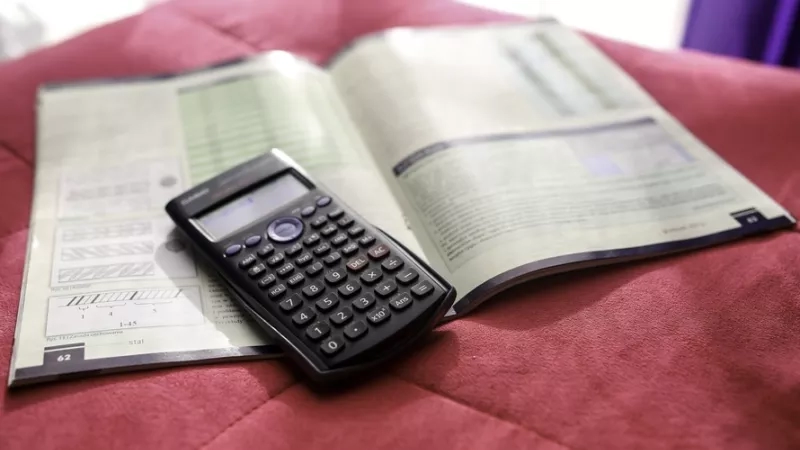 Calculator and book on a bed showing how to revise with a calculator.