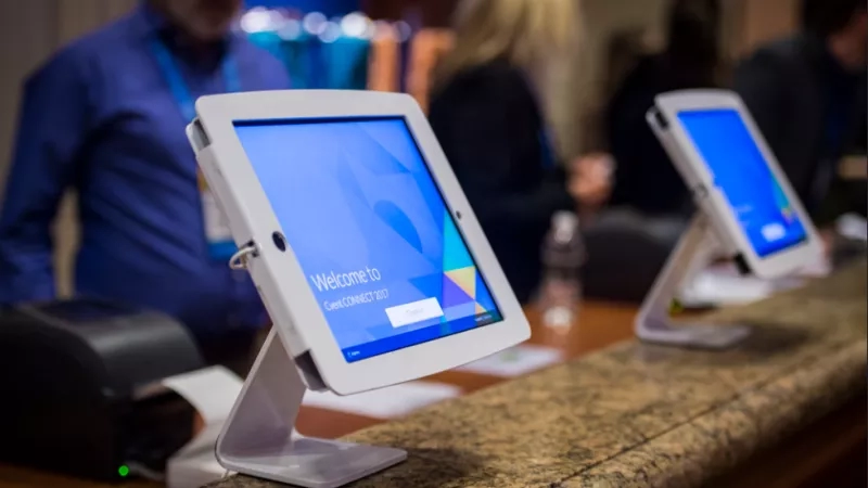 Two tablets with a welcome screen on them sit on a desk at a conference event.