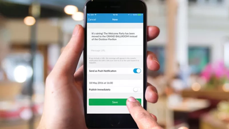 A hand holding a phone displaying a notification of a location change at an event.