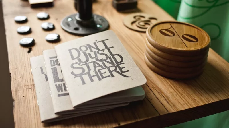 A desk has designer typography brochures and coasters on it.