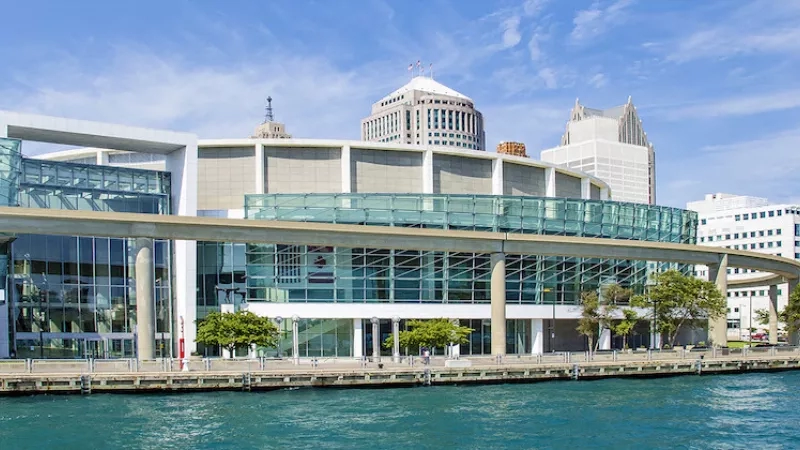 A view of Cobo Center in Detroit, Michigan, with waterfront and modern architecture under a clear sky.