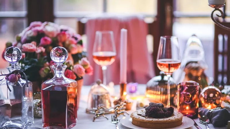 A table is set for dinner with a bottle of wine and a cake on it.