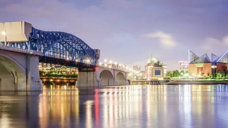The Tennessee Aquarium in Chattanooga with a bridge over a body of water and buildings in the background.