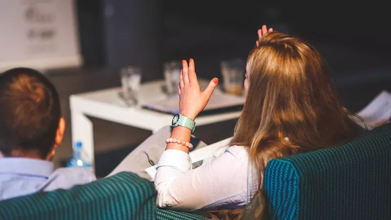 A woman raises her hands as she listens to a speaker in a meeting at the hotel.