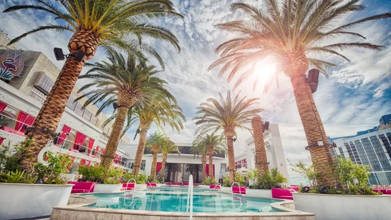 Palm trees, pool, and modern architecture at Luxor Hotel, showcasing vacation luxury with vibrant colors and lush landscaping.