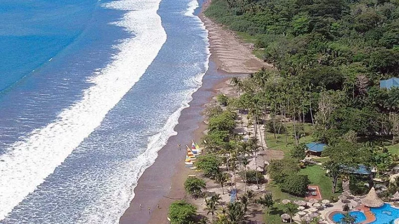 The aerial view of Barceló Tambor Beach Resort features a pool, lush greenery, and the Pacific Ocean.