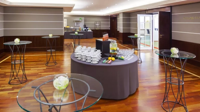 The Hotel Bristol Berlin features an event space with a wooden floor, round tables, and modern decor.