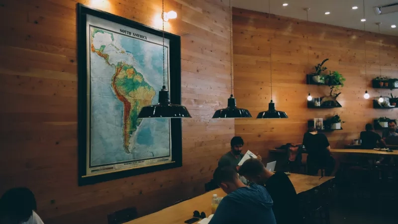 People reading books in a room with wooden walls and hanging lamps at Hotel Guest.