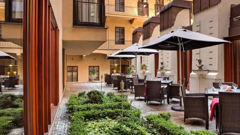 Hotel Majestic Plaza Prague with tables, umbrellas, and greenery, showcasing architecture and ambiance.