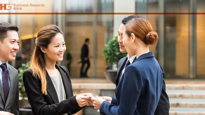 IHG business rewards in Greater China with four business people exchanging business cards in an office building.