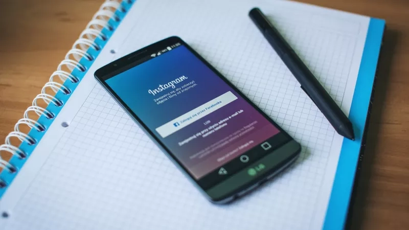 Black phone on a paper with Instagram login page displayed and a pen next to it.