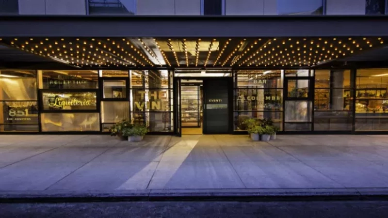 Kimpton Eventi: A stylish hotel entrance with a bar, wine, and liquor signage, and a welcoming ambiance.