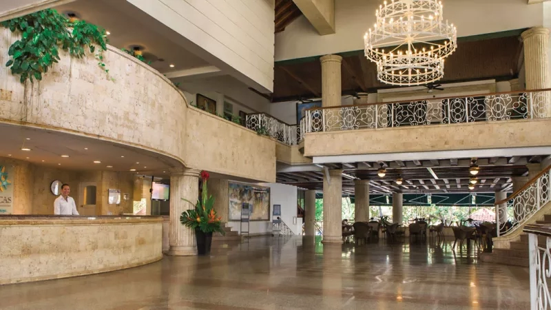 The Casa de Playa lobby with an attendant, a chandelier, and a staircase to the right.