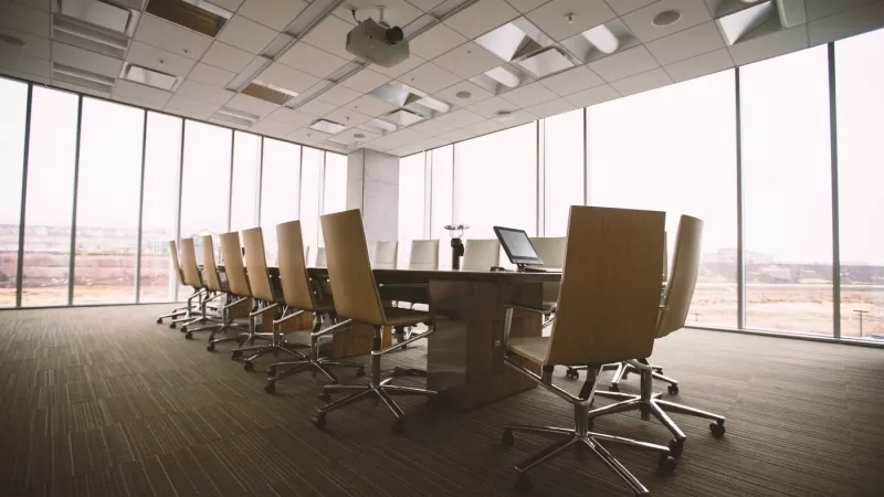 Modern meeting room with a conference table and chairs near the glass windows in the day time.