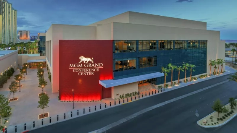 An exterior shot of the MGM Grand Conference Center at dusk with palm trees and an illuminated sign.