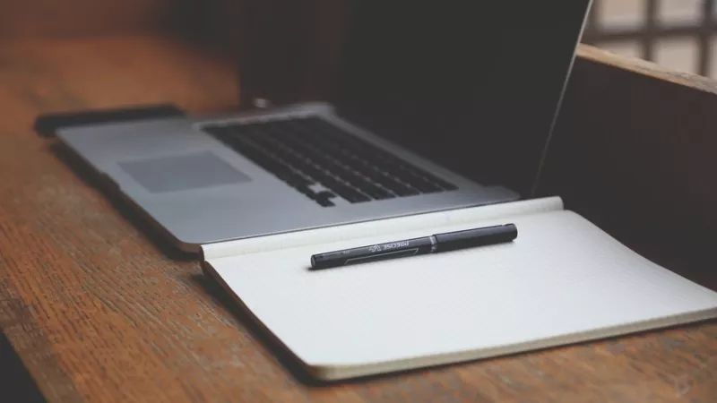A notebook and a computer on a desk, creating a chill and relaxing ambiance.