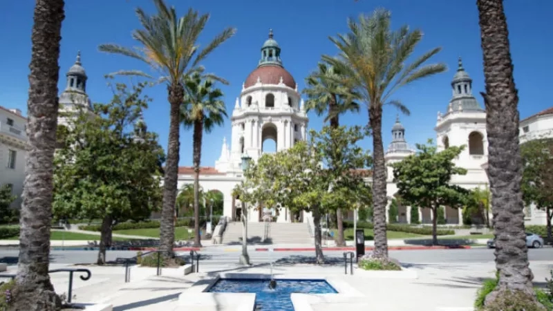 Pasadena City Hall with lush trees and a fountain in front on a sunny day.