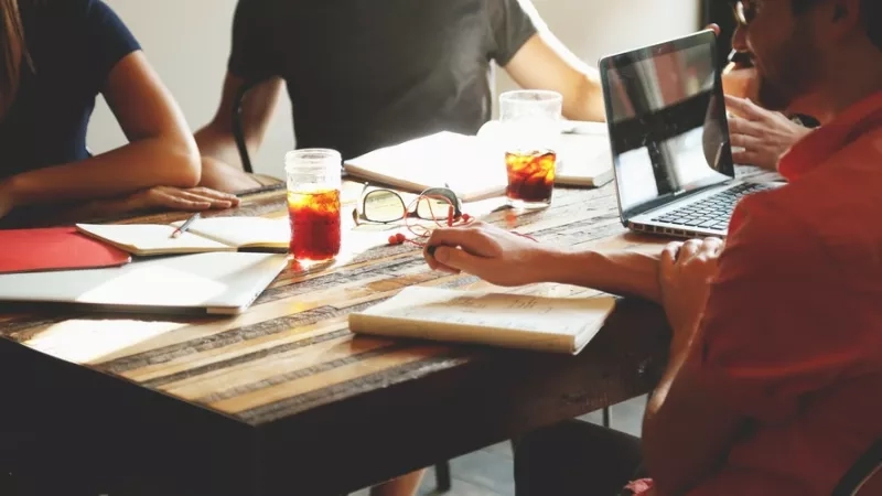 People sitting around a table with coffee and tea in a meeting.