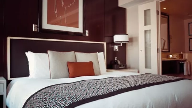 A bed with pillows, a headboard, a nightstand, and a picture frame on top of the wall