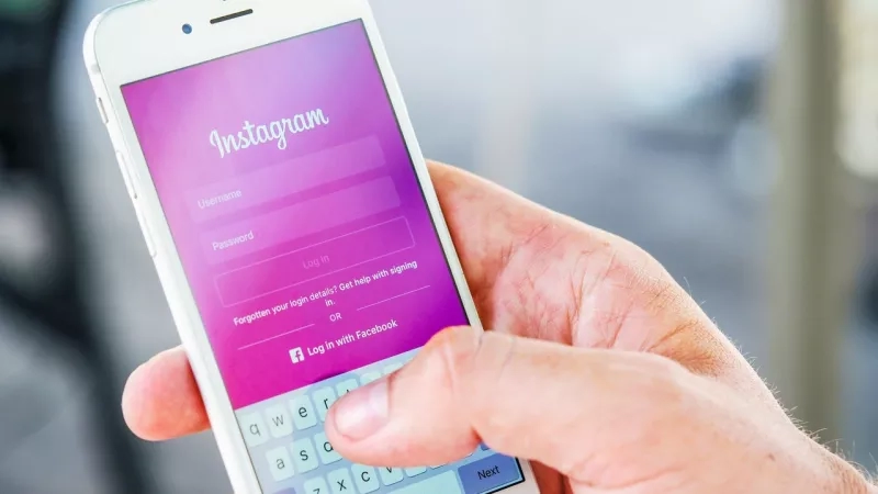 A person holds an iPhone with the Instagram app displayed on the screen.