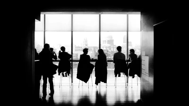 Black and white photo of people sitting in front of large window at the Tate Modern museum.