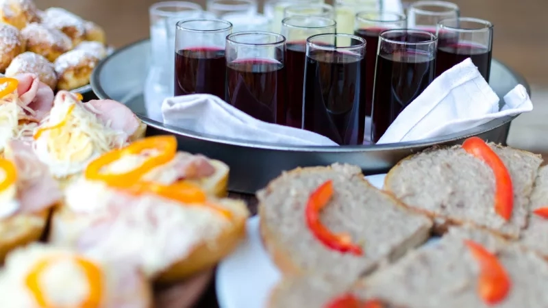 Appetizers, drinks, and a white napkin are in a silver bowl for a party at Hotel de la Cigogne.