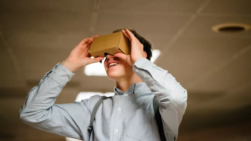 A man wearing a cardboard VR headset and smiling, showing a fun, immersive experience.