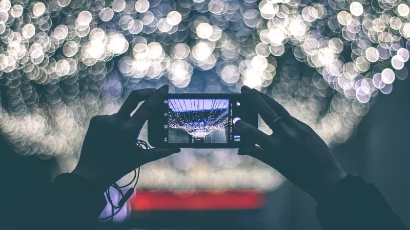 A person holding a cellphone capturing the ceiling of a building at night.