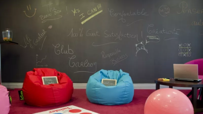 Brainstorming area with a wall of scribbles, beanbags, and a laptop on a table