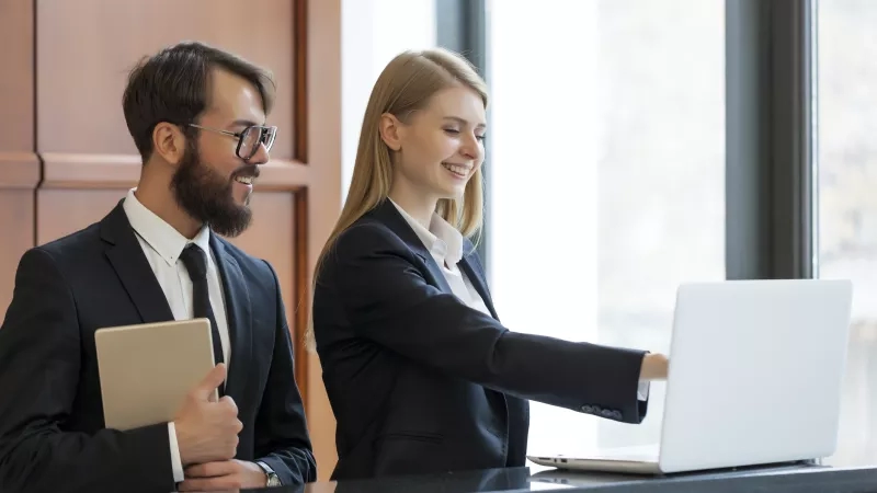 A smiling front desk employee assisting a guest at the reservation desk.