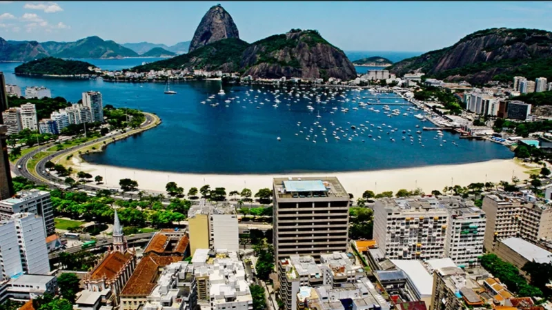 A cityscape with many buildings, a large body of water, and a mountain in the background.