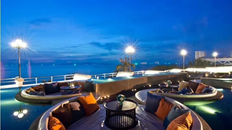 A serene poolside with round seating and night view at Royal Hotels Group.