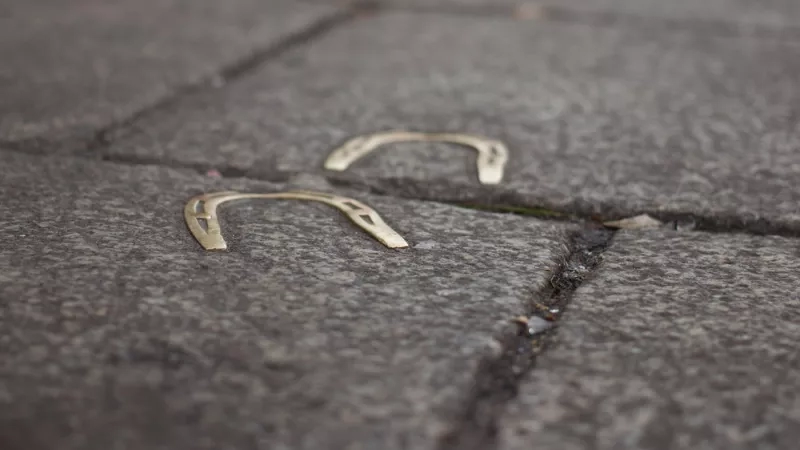 Two horseshoes on the sidewalk are horseshoes for luck on a walkway with a grey-brown stone tile.