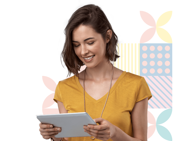 A woman in a yellow shirt is smiling while holding a tablet in front of a green background.