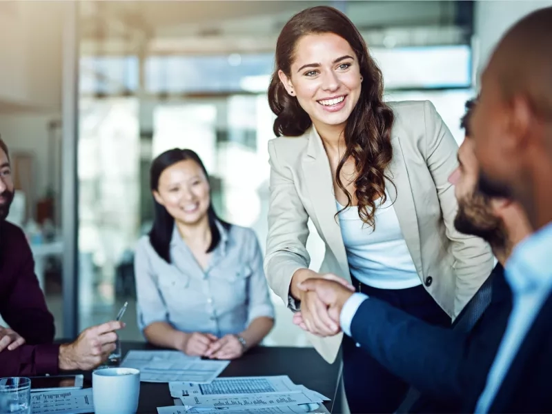 Woman shaking hands with business people with a smile on her face.