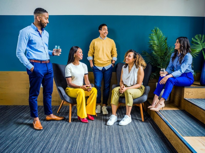 Diverse professionals in modern office, smiling and engaged, illustrating inclusive workplace culture and positive atmosphere.