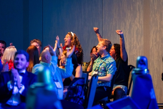 A group of people with their hands up cheering for someone at an event.
