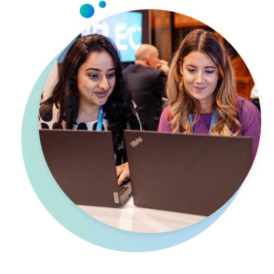 Two women in an office setting working on their laptops with a blue circle around them.